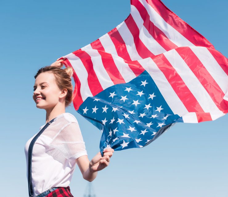 happy-young-woman-holding-united-states-flag-again-BESAKW2